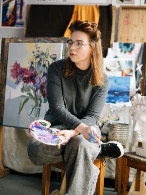pexels-photo-5033996-5033996 A female artist sitting in her studio, holding a paint palette, while contemplating her artworks. Art techniques for beginners. Beginner art lessons.