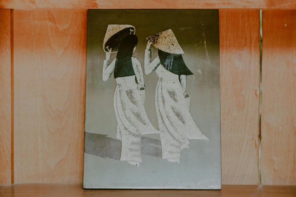 Elegant traditional wall art depicting two figures in cultural attire on a wooden background. sketching tricks. portrait drawing for beginners.