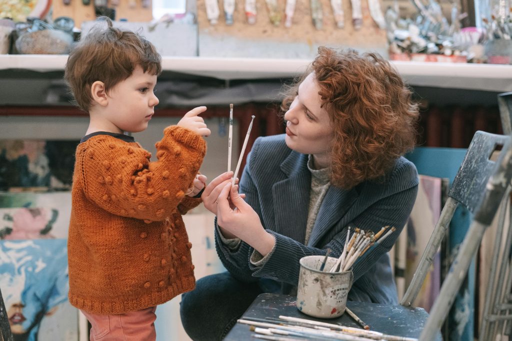 A mother and her young child painting together in a cozy art studio setting. pencil sketch drawing. simple pencil drawing.